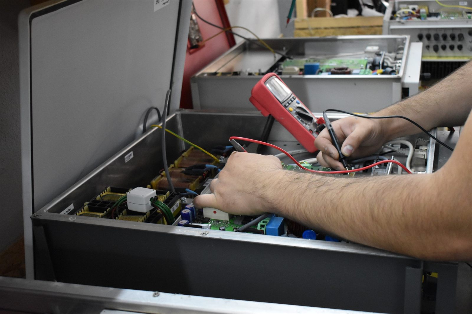 Technician taking measurements inside an open high-power inverter